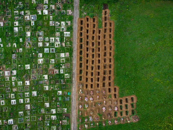 Open empty graves among the green meadow, aerial drone view of emty tombs.