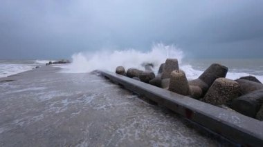 Powerful storm waves crashing against a pier, first-person view of dramatic ocean spray and rough sea.