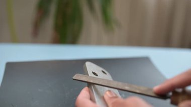 Close-up of a person sharpening a metal part with a hand file, detailed view of manual tool work and craftsmanship process.