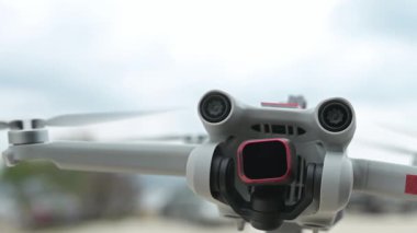 Dönen pervaneleri ve parlayan ışıkları olan uçan bir İHA 'nın yavaş çekim yakın çekimi, bulutlu gökyüzü arka planına karşı kamera titreşimleri ve sensörleri gösteriyor.