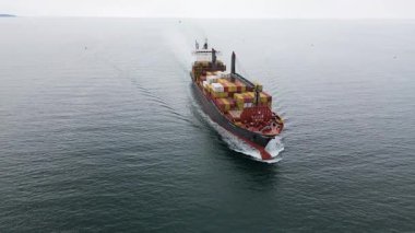Limana yaklaşan renkli konteynırlar taşıyan büyük bir kargo gemisinin hava görüntüsü. Deniz taşımacılığı ve uluslararası nakliye kavramı.