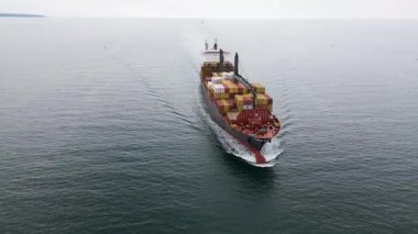 Limana yaklaşan renkli konteynırlar taşıyan büyük bir kargo gemisinin hava görüntüsü. Deniz taşımacılığı ve uluslararası nakliye kavramı.