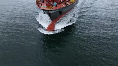 Denizi yarıp geçen büyük bir kargo gemisinin havadan yakından görüntüsü pruvada dalgalar yaratıyor. Deniz taşımacılığı ve küresel nakliye kavramı.