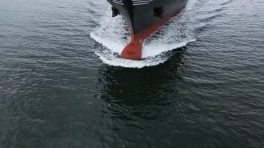 Denizi yarıp geçen büyük bir kargo gemisinin havadan yakından görüntüsü pruvada dalgalar yaratıyor. Deniz taşımacılığı ve küresel nakliye kavramı.