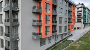 Renkli cepheli, geniş pencereli ve balkonlu, çağdaş konut mimarisi sergilenen yeni tamamlanmış modern apartman manzarası..