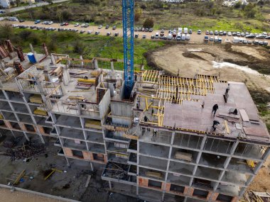 İskelelerle kaplı çok katlı bir konut inşaatı, dış duvarları bitiren işçiler, detaylı bir kentsel gelişim sahnesinde yakalandı..