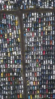 Yoğun sırada dizilmiş eski, hasarlı ve kullanılmayan araçlarla dolu terk edilmiş bir araba mezarlığının yukarıdan görünüşü. Çürüme, atık, geri dönüşüm ve unutulmuş ulaşım kavramı.