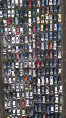 Yüzlerce eski, hasarlı ve kullanılmayan aracın yoğun sırada dizildiği terk edilmiş bir araba mezarlığının yukarıdan görünüşü. Çürüme, geri dönüşüm ve unutulmuş ulaşım kavramı.