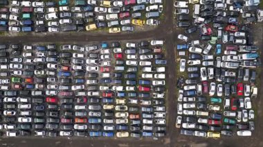 Yüzlerce eski, hasarlı ve kullanılmayan aracın yoğun sırada dizildiği terk edilmiş bir araba mezarlığının yukarıdan görünüşü. Çürüme, geri dönüşüm ve unutulmuş ulaşım kavramı.