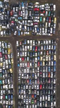 Yüzlerce eski, hasarlı ve kullanılmayan aracın yoğun sırada dizildiği terk edilmiş bir araba mezarlığının yukarıdan görünüşü. Çürüme, geri dönüşüm ve unutulmuş ulaşım kavramı.