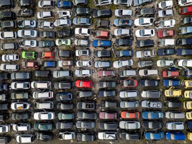 Yoğun sırada dizilmiş eski, hasarlı ve kullanılmayan araçlarla dolu terk edilmiş bir araba mezarlığının yukarıdan görünüşü. Çürüme, atık, geri dönüşüm ve unutulmuş ulaşım kavramı.