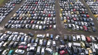 Sıraya dizilmiş eski, hasarlı ve parçalanmış araçlarla dolu terk edilmiş bir araba mezarlığının hava görüntüsü. Otomotiv atıkları, geri dönüşüm ve çevresel bozulma kavramı.