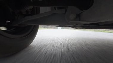 Arabanın altına monte edilmiş bir aksiyon kamerasından alınan düşük açılı POV sürücü videosu, güçlü yol hareketleriyle süspansiyon ve tekerlek hareketlerini gösteriyor. Otomotiv iniş alanı görünümü, hız, araç dinamiği, seyahat ve ulaşım.