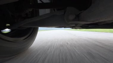 Arabanın altına monte edilmiş bir aksiyon kamerasından alınan düşük açılı POV sürücü videosu, güçlü yol hareketleriyle süspansiyon ve tekerlek hareketlerini gösteriyor. Otomotiv iniş alanı görünümü, hız, araç dinamiği, seyahat ve ulaşım.