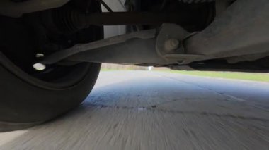 Arabanın altına monte edilmiş bir aksiyon kamerasından alınan düşük açılı POV sürücü videosu, güçlü yol hareketleriyle süspansiyon ve tekerlek hareketlerini gösteriyor. Otomotiv iniş alanı görünümü, hız, araç dinamiği, seyahat ve ulaşım.