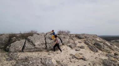 Kayalık arazide kolları açık duran anne ve çocuğun hava görüntüsü. Aile özgürlüğün ve doğanın tadını çıkarıyor. Açık arazide neşe, bağlantı ve açık hava keşiflerini ifade ediyor..