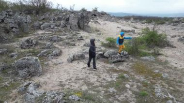 Kayalık arazide yürüyen iki çocuk ve kireçtaşı oluşumları. Vahşi arazide keşif ve macera, merak, hareket ve doğa ile bağlantıyı gösteriyor..