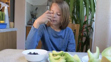 Evde yemek yiyip içki içen çocuk. Bir çocuğun yemek ve içecekten keyif aldığı sakin bir gün, sağlıklı bir rutin, aile hayatı, sıradan bir ev hayatı, doğal çocukluk aktivitesi..