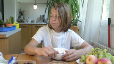 Evde yemek yiyip içki içen çocuk. Bir çocuğun yemek ve içecekten keyif aldığı sakin bir gün, sağlıklı bir rutin, aile hayatı, sıradan bir ev hayatı, doğal çocukluk aktivitesi..