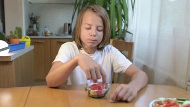 Evde yemek yiyip içki içen çocuk. Bir çocuğun yemek ve içecekten keyif aldığı sakin bir gün, sağlıklı bir rutin, aile hayatı, sıradan bir ev hayatı, doğal çocukluk aktivitesi..