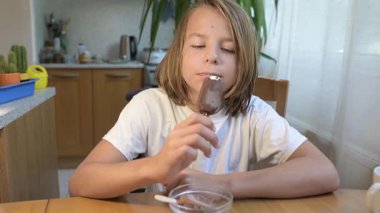 Evde yemek yiyip içki içen çocuk. Bir çocuğun yemek ve içecekten keyif aldığı sakin bir gün, sağlıklı bir rutin, aile hayatı, sıradan bir ev hayatı, doğal çocukluk aktivitesi..