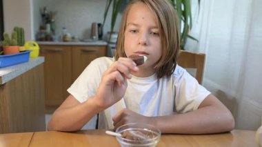 Evde yemek yiyip içki içen çocuk. Bir çocuğun yemek ve içecekten keyif aldığı sakin bir gün, sağlıklı bir rutin, aile hayatı, sıradan bir ev hayatı, doğal çocukluk aktivitesi..
