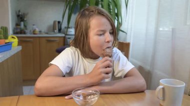 Evde yemek yiyip içki içen çocuk. Bir çocuğun yemek ve içecekten keyif aldığı sakin bir gün, sağlıklı bir rutin, aile hayatı, sıradan bir ev hayatı, doğal çocukluk aktivitesi..