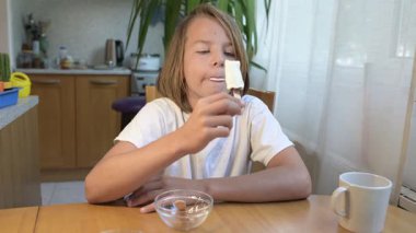 Evde yemek yiyip içki içen çocuk. Bir çocuğun yemek ve içecekten keyif aldığı sakin bir gün, sağlıklı bir rutin, aile hayatı, sıradan bir ev hayatı, doğal çocukluk aktivitesi..