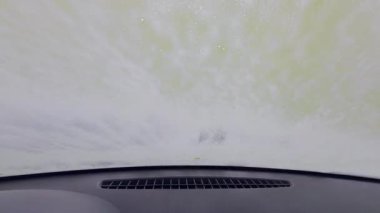 Bir işçi ön cama köpük ve su püskürtürken araba yıkama servisi aracın içinden görüldü. Cam aracılığıyla POV görünümü, kentsel self-servis araba yıkama, günlük rutin, gerçek yaşam anı.