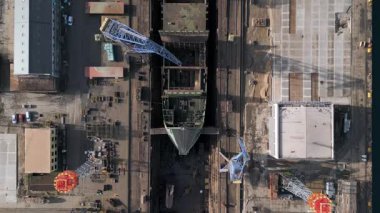 Endüstriyel bir limandaki kuru rıhtım, vinç ve kargo gemileriyle dolu bir gemi tamirhanesinin havadan görüntüsü. Büyük tersane altyapısı, deniz sanayii, lojistik ve su kenarı onarım operasyonları.