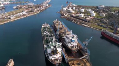 Endüstriyel bir limandaki kuru rıhtım, vinç ve kargo gemileriyle dolu bir gemi tamirhanesinin havadan görüntüsü. Büyük tersane altyapısı, deniz sanayii, lojistik ve su kenarı onarım operasyonları.