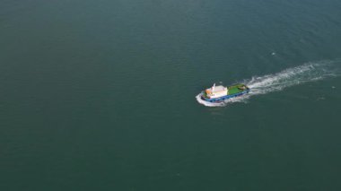 Açık denizde ilerleyen bir römorkörün havadan görünüşü koyu mavi suda beyaz bir iz bırakıyor. Denizcilik çekici gemi hareket halinde, gemi ve liman konseptleri için yukarıdan yakalandı..