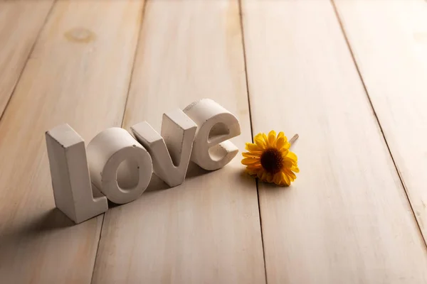 Betonowe Litery Mówiące Miłość Żółtym Kwiatem Białej Umytej Drewnianej Desce — Zdjęcie stockowe