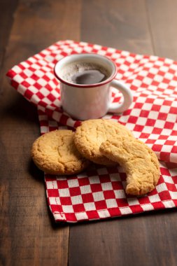 Ev yapımı çıtır kurabiyeler ve ahşap masada espresso fincanı.
