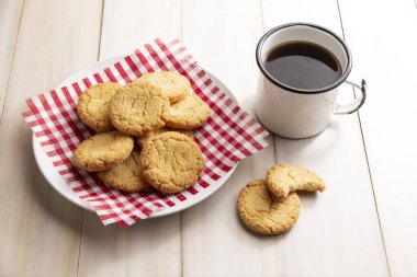 Ev yapımı çıtır kurabiyeler ve beyaz ahşap kırsal masada bir kahve fincanı.