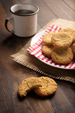 Ev yapımı çıtır kurabiyeler ve ahşap kırsal masada bir kahve fincanı.