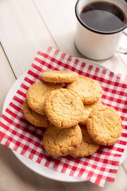 Ev yapımı çıtır kurabiyeler ve ahşap kırsal masada bir kahve fincanı.