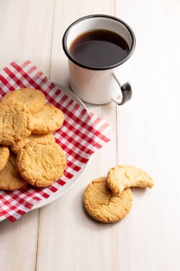 Ev yapımı çıtır kurabiyeler ve tahta beyaz kırsal masada bir kahve fincanı.