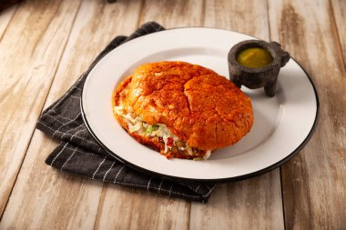 Pambazo. Meksika sandviçi kırmızı sosla marine edildi ve geleneksel olarak Meksika sokak yemeklerinin klasik bir örneği olan patates ve sucukla dolduruldu..