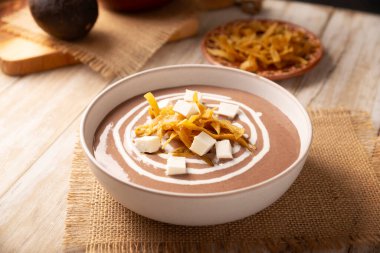Creamy bean soup. In Mexico known as Crema de Frijoles, nutritious homemade food recipe, commonly accompanied with cheese, cream, avocado and corn tortilla cut into strips and fried.