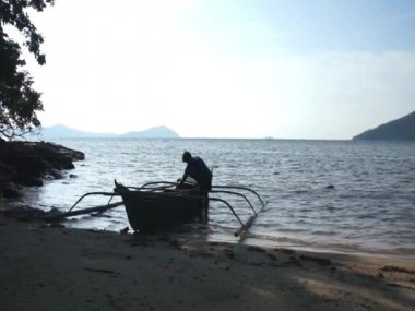 Onun ahşap tekne yakınındaki Filipino balıkçı. Tropikal deniz.