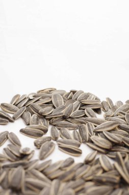Close-up image of natural sunflower seeds scattered on a clean white background. The high-resolution photo highlights the texture, shape, and color of the seeds in detail. Ideal for packaging design, food labels, agricultural websites, and sunflower 