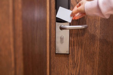 Genç bir kadın modern otel odasının kapısını elektronik anahtar kartıyla açıyor. Seyahat, konukseverlik, güvenlik, tatil, iş gezisi ve çağdaş otel teknolojisi kavramı.