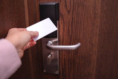 Genç bir kadın modern otel odasının kapısını elektronik anahtar kartıyla açıyor. Seyahat, konukseverlik, güvenlik, tatil, iş gezisi ve çağdaş otel teknolojisi kavramı.