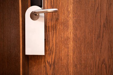 Kapı tokmağı boş kapı askısının maketi. Boş beyaz el ilanı modeli kapı koluna asılmış. Broşür tasarımı. İşareti bozmayın. Otel odası temiz askı. Sinyali bozmayın..