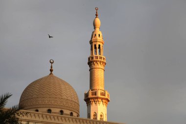 Dubai 'de. UAE01.25. 2022 yılı. Altın ışık, Dubai 'deki Musabah Bin Rashid El Fattan Camii' ni aydınlatıyor. Zarif kubbesini, minaresini ve etrafındaki palmiye ağaçlarını yumuşak bir gökyüzüne vurguluyor..