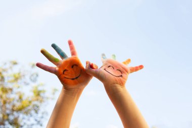 Gülümseyen yüzlü parlak boyalı eller neşe, masumiyet, yaratıcılık ve neşe dolu birlik çocukluk ve beraberliğin coşkulu bir kutlaması.