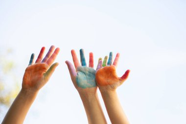 Gülümseyen yüzlü parlak boyalı eller neşe, masumiyet, yaratıcılık ve neşe dolu birlik çocukluk ve beraberliğin coşkulu bir kutlaması.