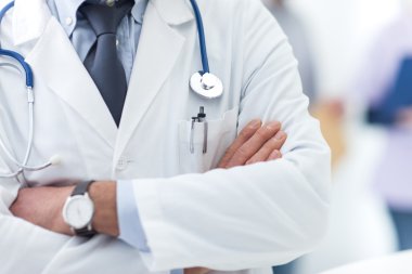 Doktor kollarını kavuşturmuş poz veriyor.