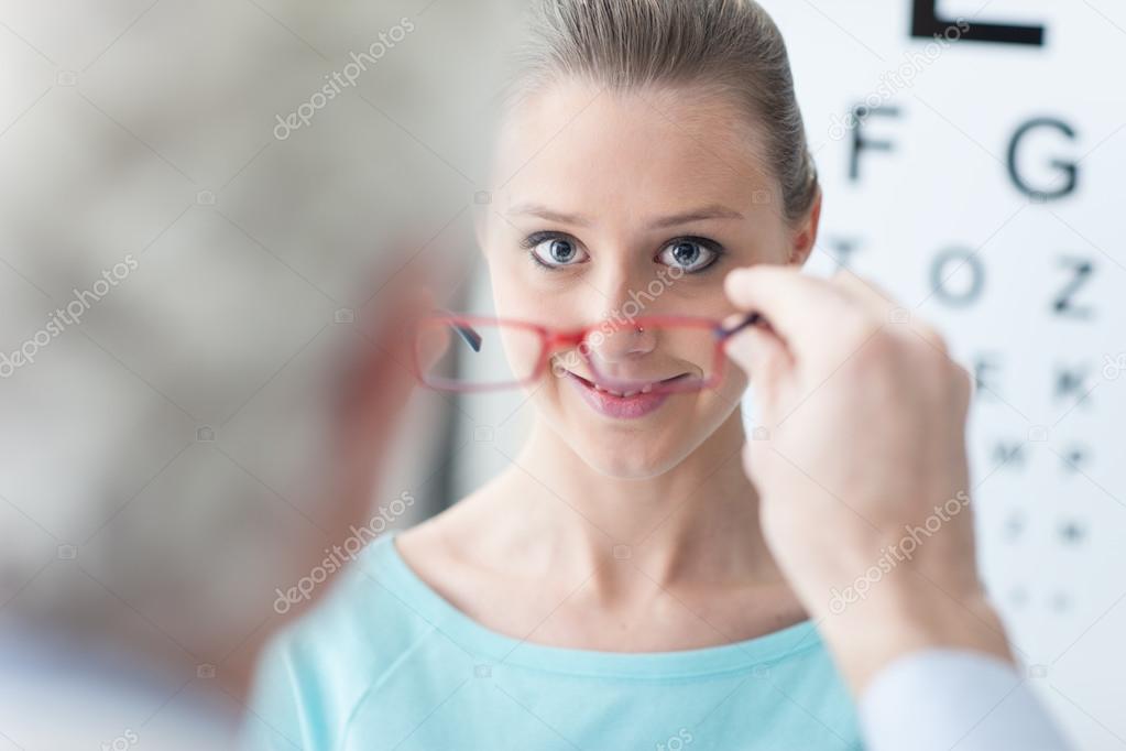 Optician giving new glasses to the patient